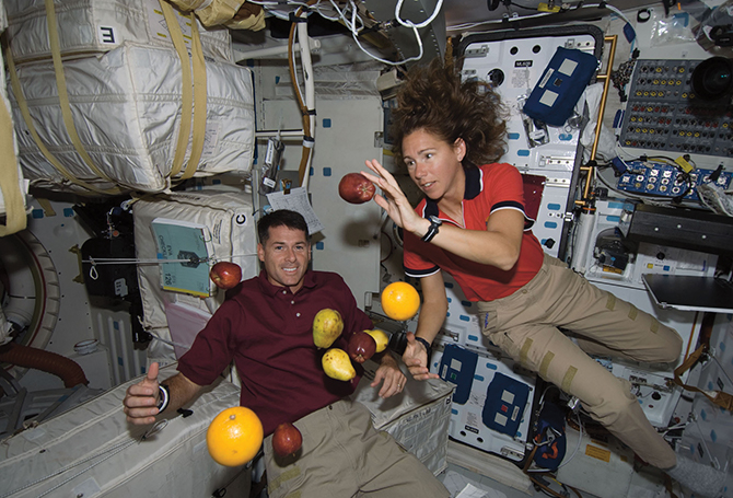 two people grabbing at floating fruit in a cramped room
