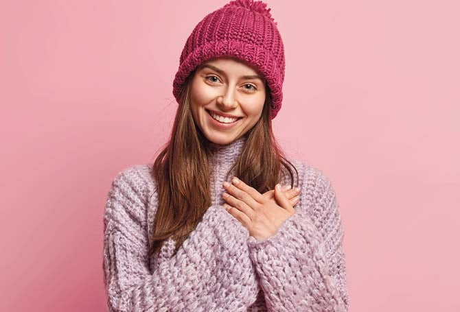 a girl smiling and holding her hands over her heart