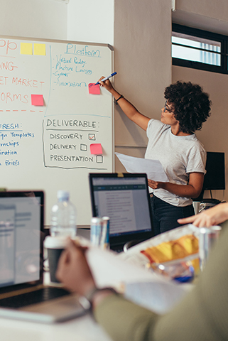 a woman writing on a whiteboard in front of other people