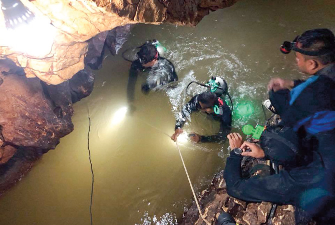 Image of cave divers with headlights swimming through water