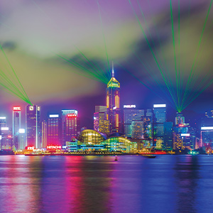 Buildings lit in different colors lighting the night sky and reflecting off the water
