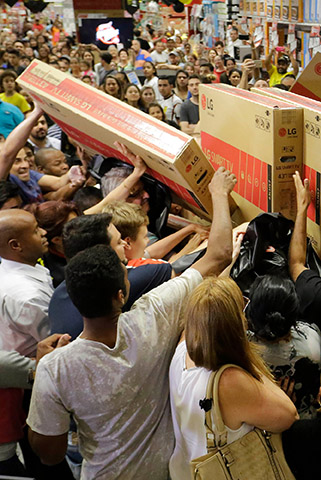 A crowd packed against each other as they grab at boxes