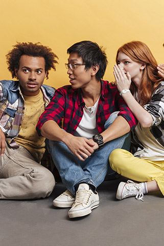 Three people listening as they whisper to one another