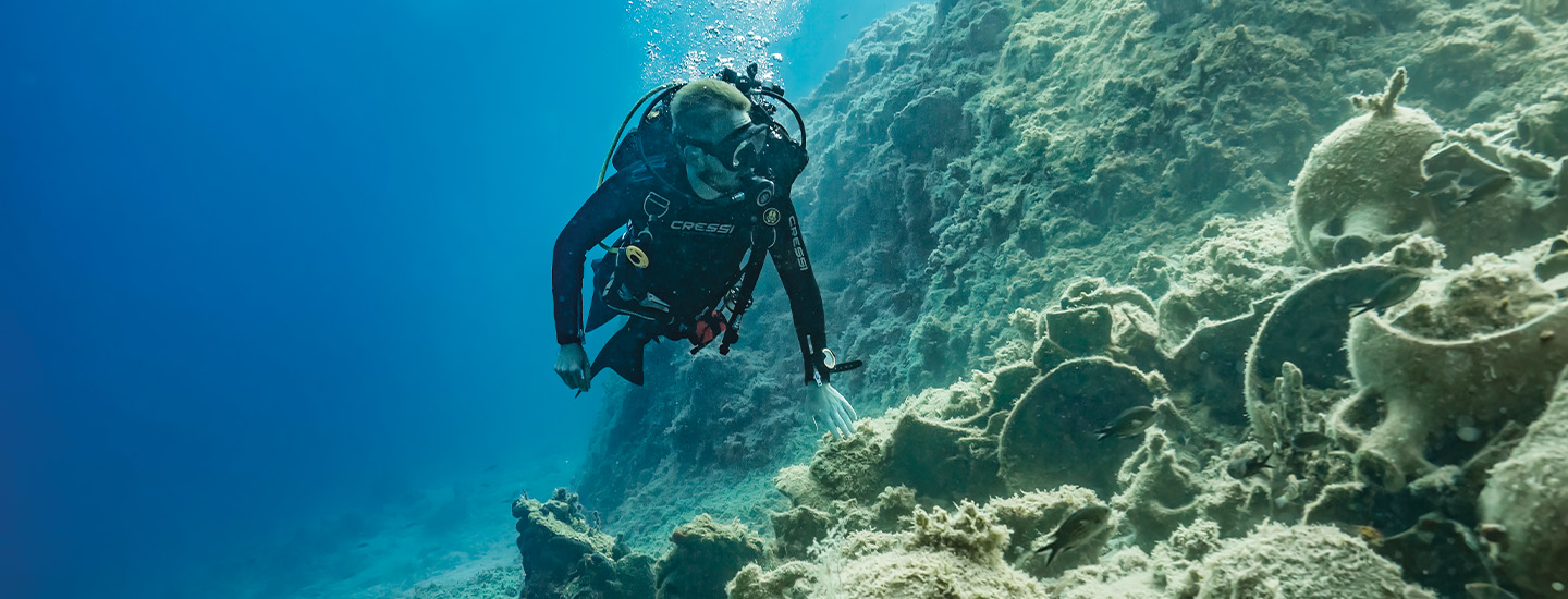 Image of a diver swimming underwater and looking for artifacts