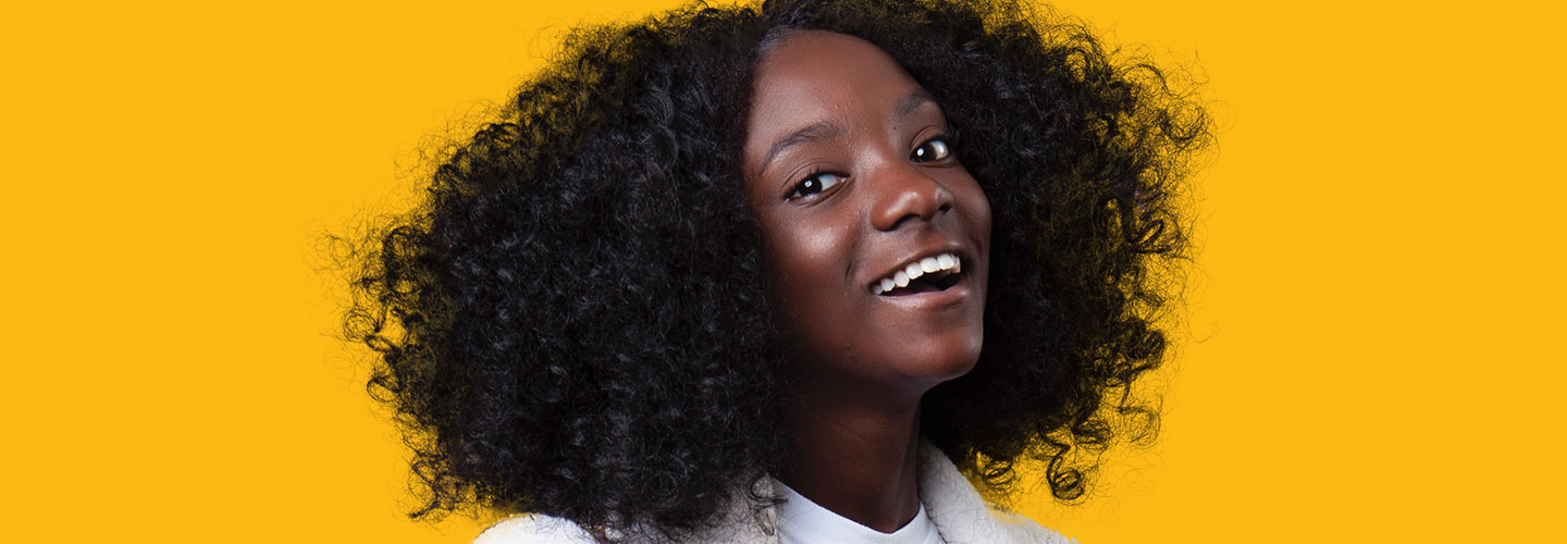 a smiling young woman in front of a yellow background